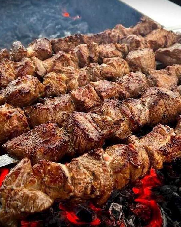 Grilling marinated shashlik preparing on a barbecue grill over charcoal.  Shashlik is a form of Shish kebab popular in Eastern Europe. Shashlyk (meaning  skewered meat) was originally made of lamb. Stock Photo